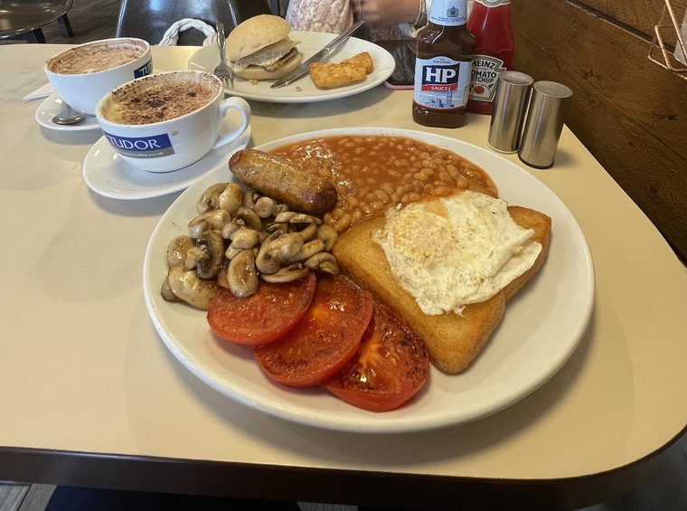 Fried egg, mushrooms, tomatoes and fried bread, cropped away from the sauce bottles.